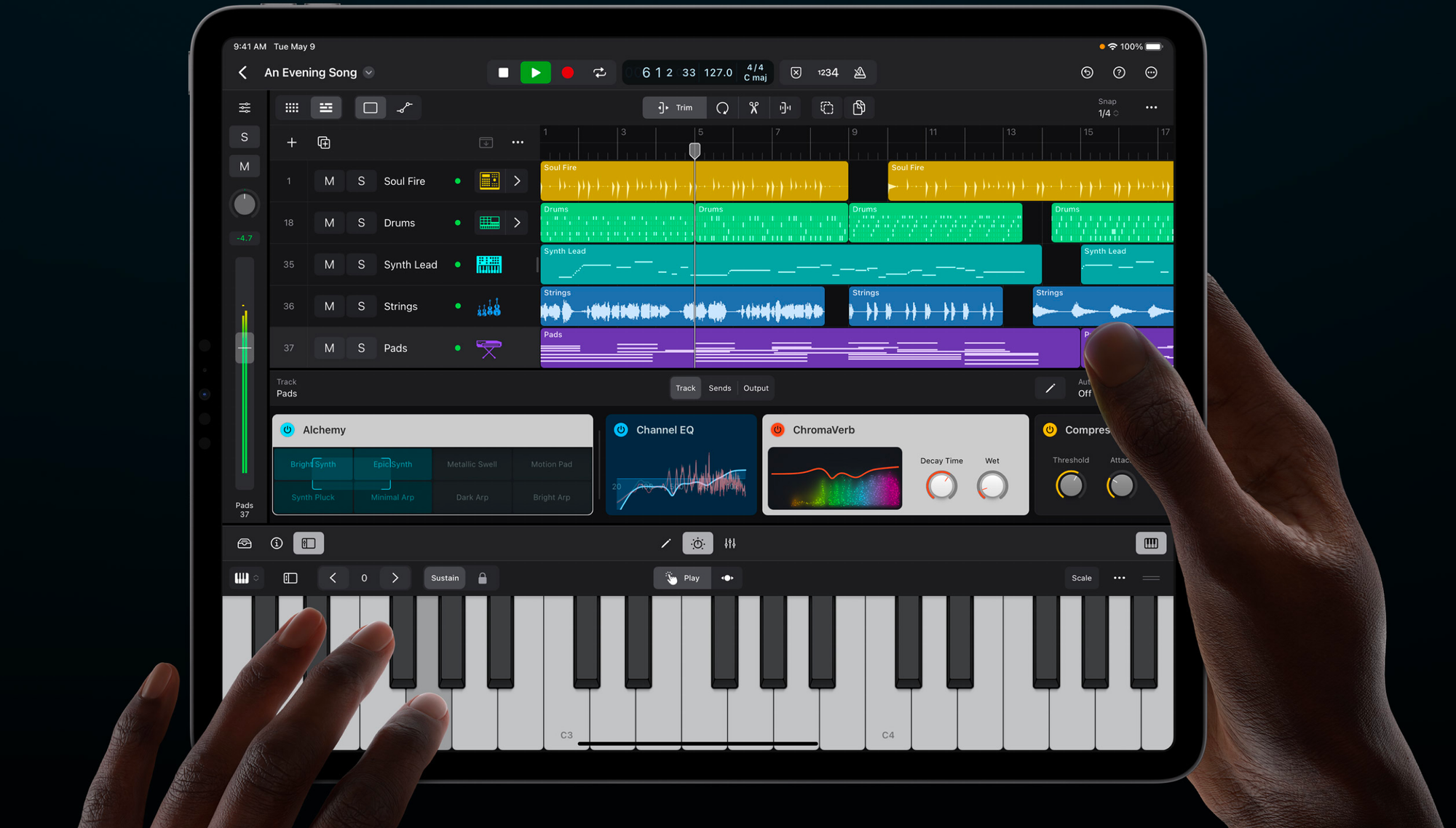 Screenshot of Logic Pro music production app on an iPad. The interface shows a multitrack view with colorful waveforms, a virtual keyboard, and audio effect modules. Hands are visible interacting with the touchscreen.