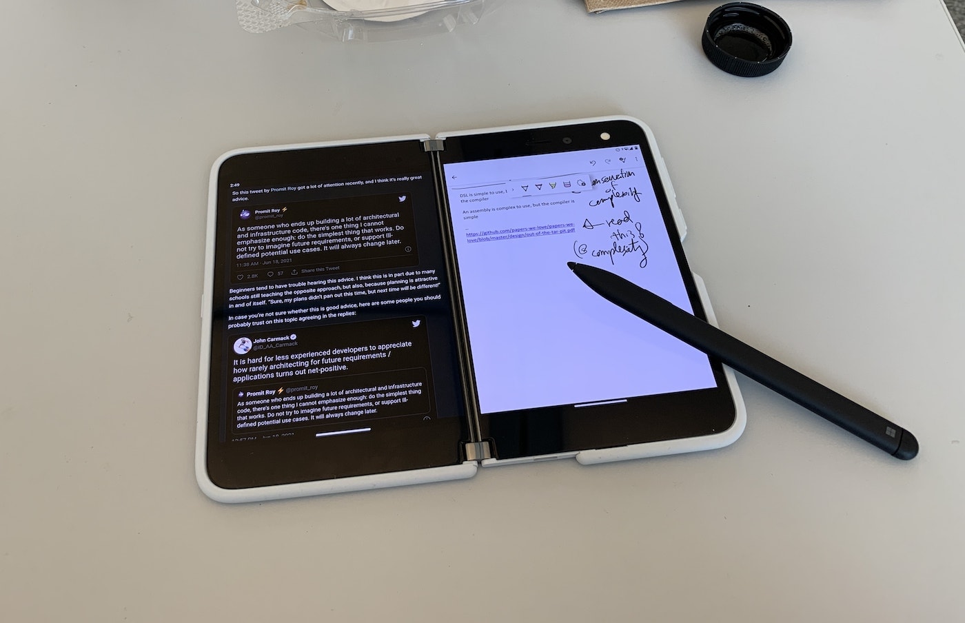A Surface Duo on a table, with a webpage on the left screen and a note-taking app with some handwritten notes on the right screen